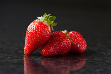 Strawberry. Red ripe strawberries on a black background with reflection. Selective focus