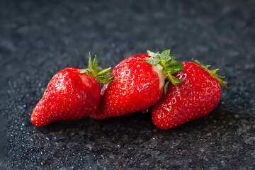 Strawberries with drops. Ripe wet strawberries on a black background with reflection. Selective focus