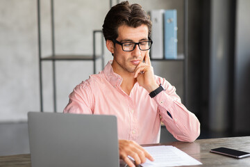 Concentrated millennial man project manager working at office