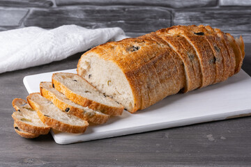 Bread with olives on a white cutting board on a gray table