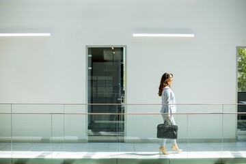 Pretty young business woman walking with briefcase in the office hallway
