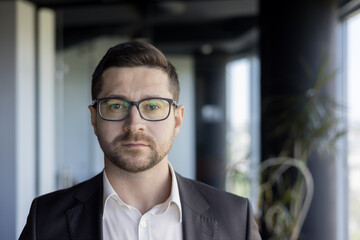 Close-up photo. Face portrait of a serious young male lawyer, notary public standing in the office...