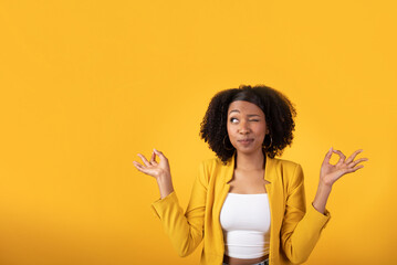 Funny curiously black lady looking with one eye at free space, meditating isolated on yellow background, studio shot - obrazy, fototapety, plakaty