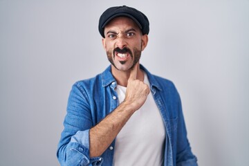 Hispanic man with beard standing over isolated background cutting throat with hand as knife, threaten aggression with furious violence