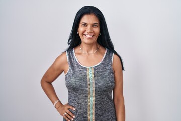 Mature hispanic woman standing over white background with a happy and cool smile on face. lucky...