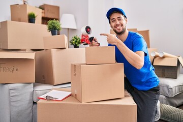 Fototapeta premium Hispanic man with beard working moving boxes smiling happy pointing with hand and finger