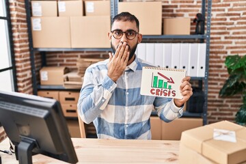 Middle east man with beard working at small business ecommerce holding crisis banner covering mouth with hand, shocked and afraid for mistake. surprised expression