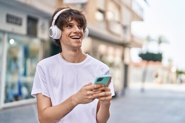 Young blond man smiling confident listening to music at street
