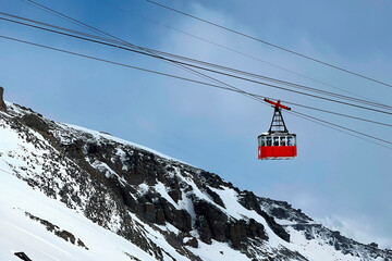 The gondola cabin is lifted by a cable car. Funicular. Landscape of snow-capped mountains. A...