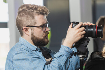 Man videomaker works on news conference modern video camera with a digital display recording an...