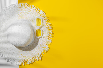 Summer flat lay white sun hat and yellow sunglasses in white plastic framed, at sunlight on bright yellow background, palm leaf shadow, copy space. Creative aesthetic Life style summer holidays