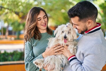 Man and woman holding dog standing together at park