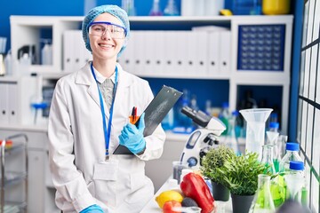 Beautiful woman working at scientist laboratory with food looking positive and happy standing and...