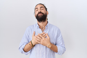 Hispanic man with beard wearing casual shirt smiling with hands on chest with closed eyes and grateful gesture on face. health concept.