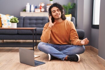 Young latin man doing yoga exercise sitting on floor at home