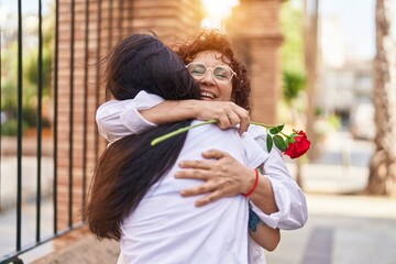 Two women mother and daughter surprise with rose at street