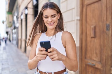 Young beautiful hispanic woman smiling confident using smartphone at street