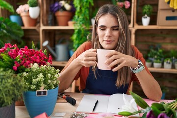 Young beautiful hispanic woman florist smiling confident drinking coffee at flower shop