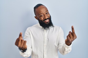 African american man standing over blue background showing middle finger doing fuck you bad expression, provocation and rude attitude. screaming excited