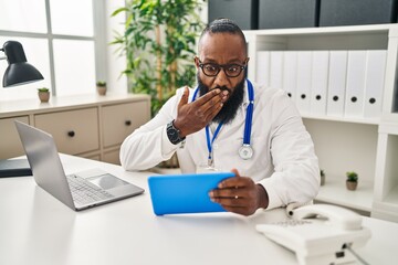 African american man working on online appointment covering mouth with hand, shocked and afraid for...