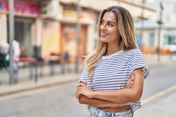 Young blonde woman standing with arms crossed gesture at street