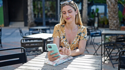 Fototapeta na wymiar Young blonde woman smiling confident using smartphone at coffee shop terrace