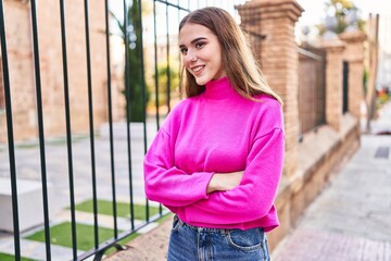 Young woman smiling confident standing with arms crossed gesture at street