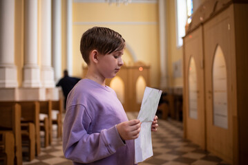 a boy stands in front of a confessional in a Catholic church, preparing for his first confession - obrazy, fototapety, plakaty