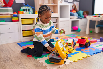 African american boy playing with toy sitting on floor at home