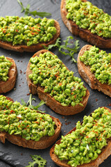 Mashed peas sourdough bread toast with sea salt flakes and chilli served on black slate