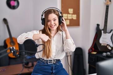 Young caucasian woman recording song at music studio pointing finger to one self smiling happy and proud