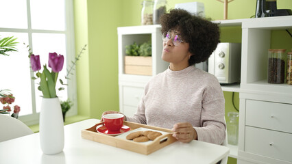 Young african american woman having breakfast sitting on table at home