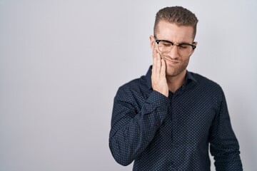 Young caucasian man standing over isolated background touching mouth with hand with painful expression because of toothache or dental illness on teeth. dentist