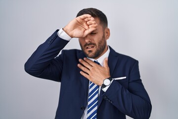 Handsome hispanic man wearing suit and tie touching forehead for illness and fever, flu and cold, virus sick