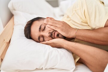 Fototapeta na wymiar Young hispanic man stressed lying on bed at bedroom