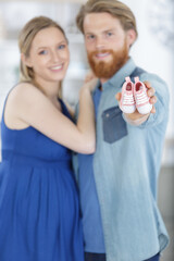 young couple with pregnant woman holding presents children clothes