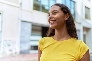 Fototapeta premium Young african american woman smiling confident looking to the side at street