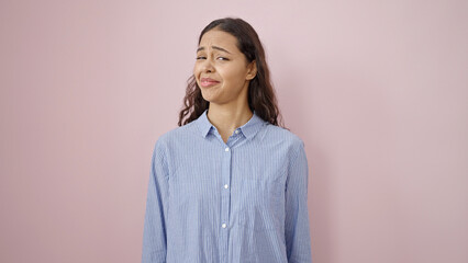 Young beautiful hispanic woman standing with doubt expression over isolated pink background