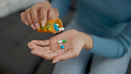 Young beautiful hispanic woman taking pills at home