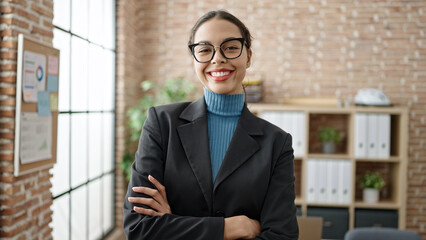 Young beautiful hispanic woman business worker smiling confident with crossed arms at office