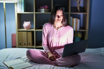 Young hispanic woman using computer laptop on the bed depressed and worry for distress, crying angry and afraid. sad expression.