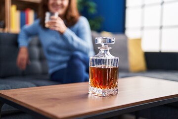 Middle age woman drinking licor sitting on sofa at home