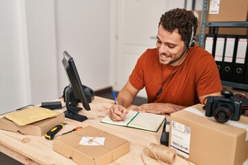 Young hispanic man ecommerce call center agent having video call writing on notebook at office