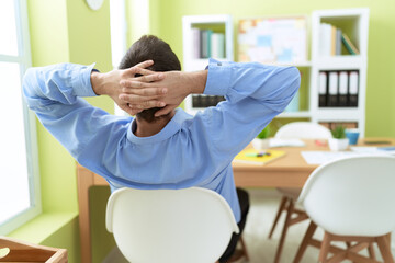 Young hispanic man business worker relaxed with hands on head at office