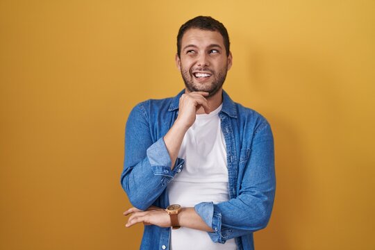 Hispanic Man Standing Over Yellow Background Thinking Worried About A Question, Concerned And Nervous With Hand On Chin