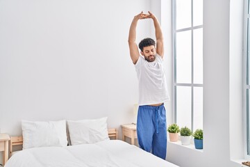 Fototapeta na wymiar Young arab man waking up stretching arms at bedroom
