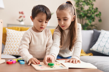 Adorable boy and girl playing with maths puzzle game standing at home