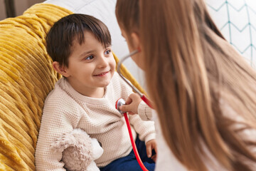 Adorable boy and girl wearing doctor uniform examining with stethoscope at home