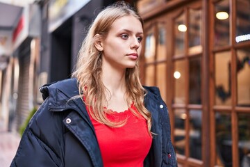 Fototapeta premium Young blonde woman looking to the side with serious expression at street