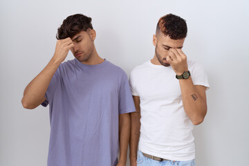 Homosexual gay couple standing over white background tired rubbing nose and eyes feeling fatigue and headache. stress and frustration concept.